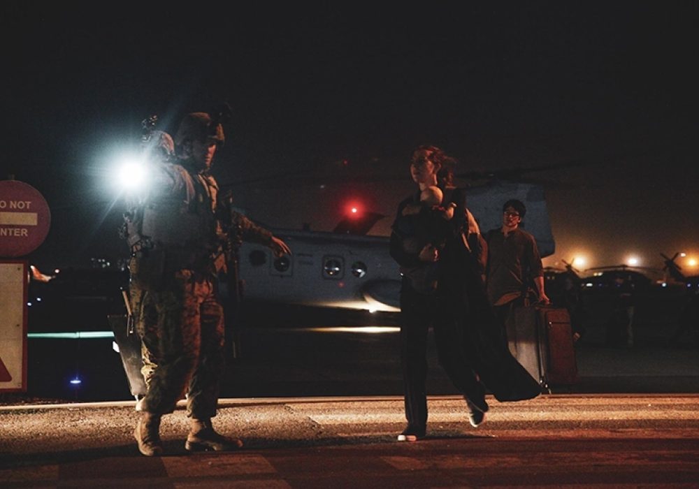 A United States Marine escorts a Department of State employee to evacuation at Hamid Karzai International Airport, Kabul, Afghanistan, August 15, 2021. CREDIT: <a href="https://en.wikipedia.org/wiki/File:Afghanistan_withdrawal_Image_3_of_7.jpg">Sgt. Isaiah Campbell/Public Domain</a>