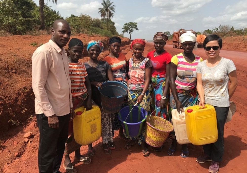 Zhang on a local mining road in Boké, Guinea, together with Mamady Koivogui, executive director of a local NGO, Association Mines Sans Pauvreté (far left) and local residents.