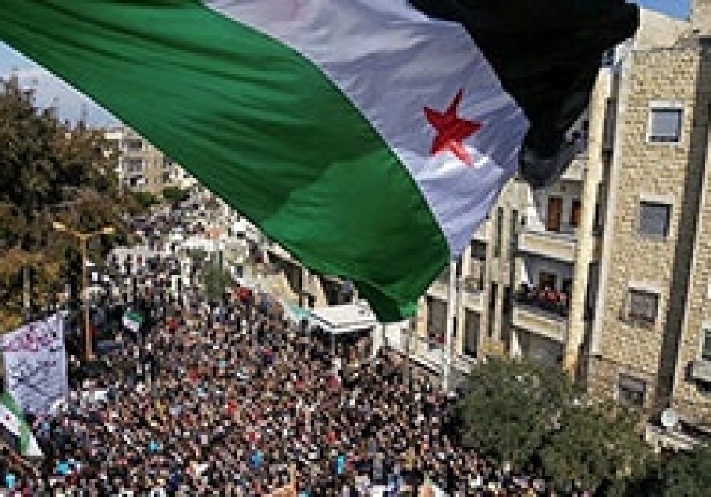 Syria independence flag flies over protesters in Idlib, <br>CREDIT: <a href="http://www.flickr.com/photos/syriafreedom/6961997081/">Freedom House</a> (<a href="http://creativecommons.org/licenses/by/2.0/deed.en">CC</a>)